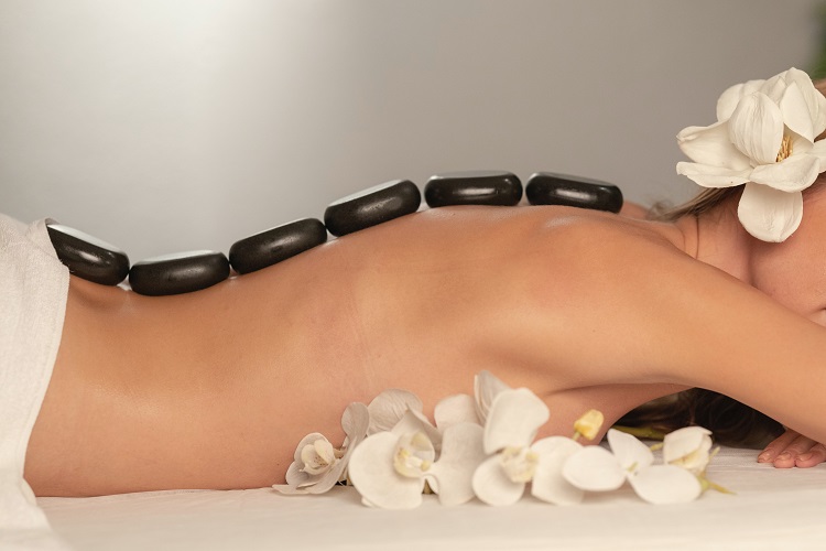 Image of woman with hot stones on her back for massage therapy.