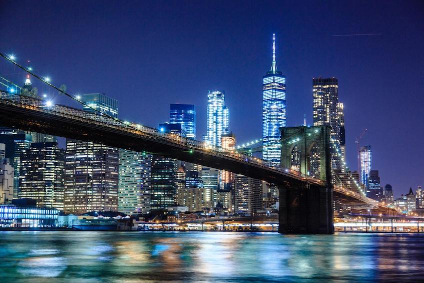 New York skyline at night with the Brooklyn Bridge.